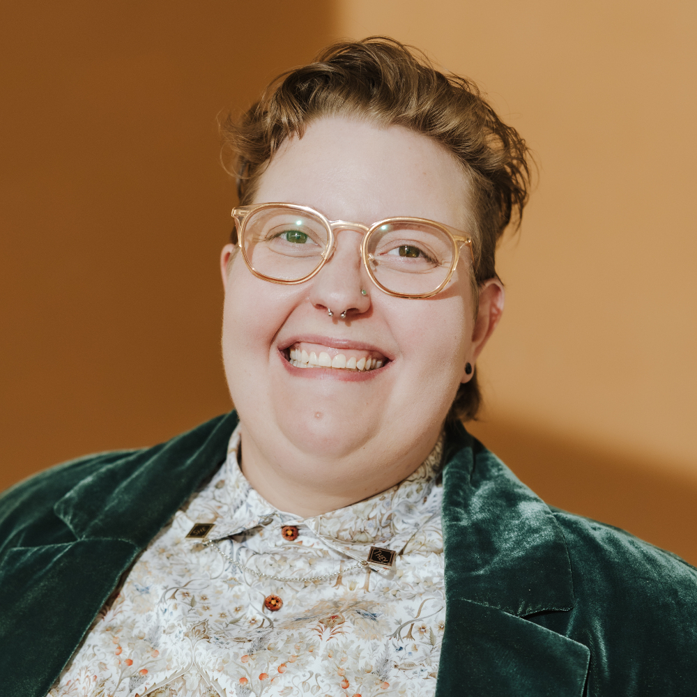 Person smiling in front of a brown wall.