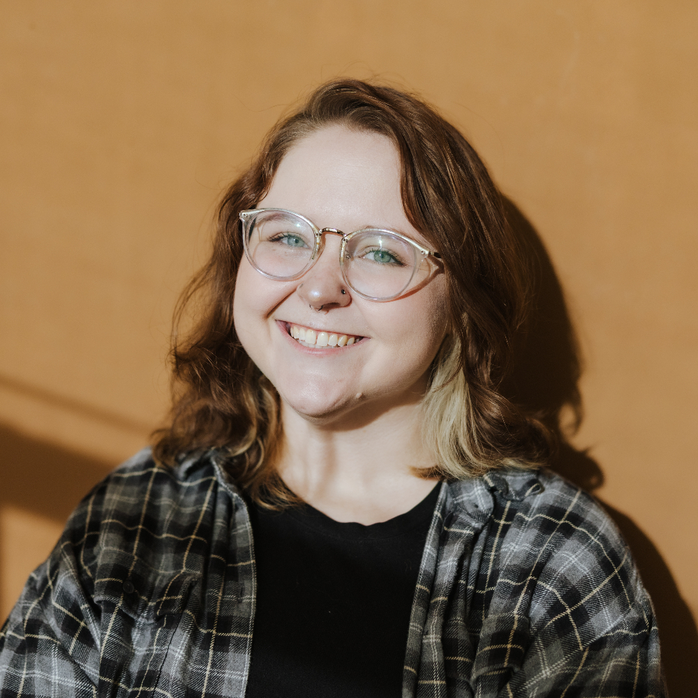 Person smiling in front of a brown background.