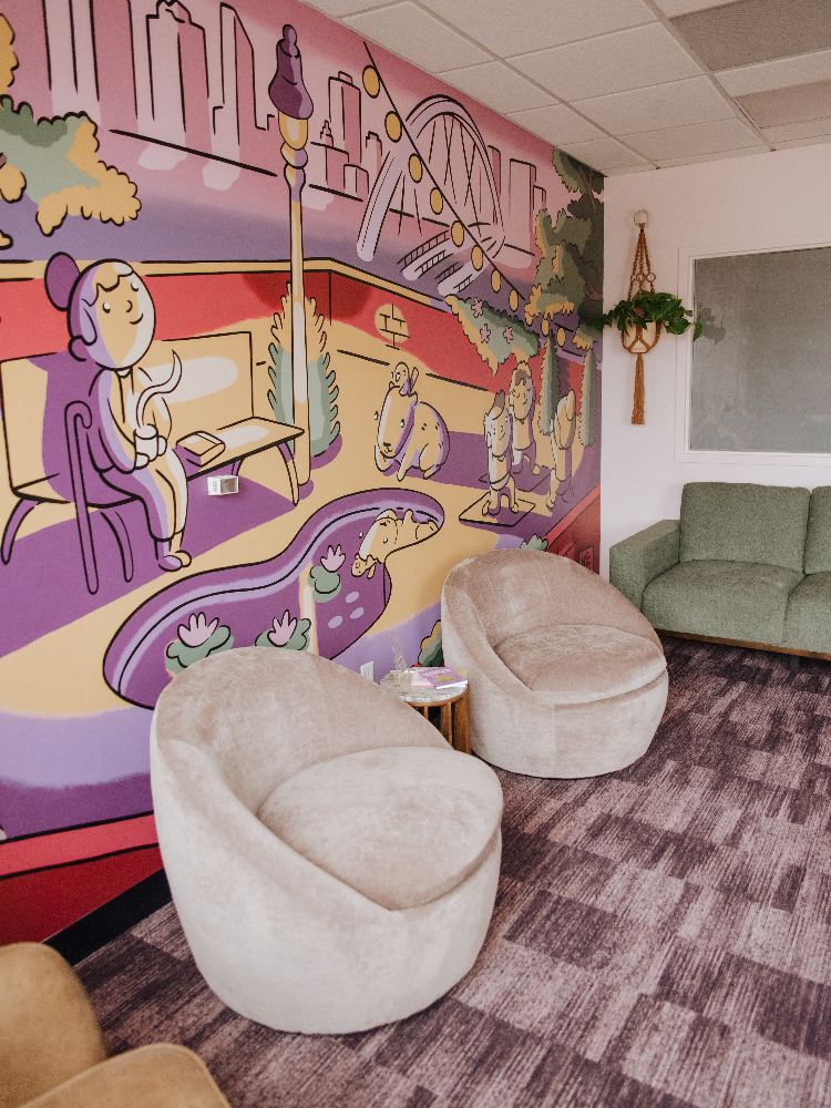 Waiting Room with cozy seating and a colorful mural on the wall.