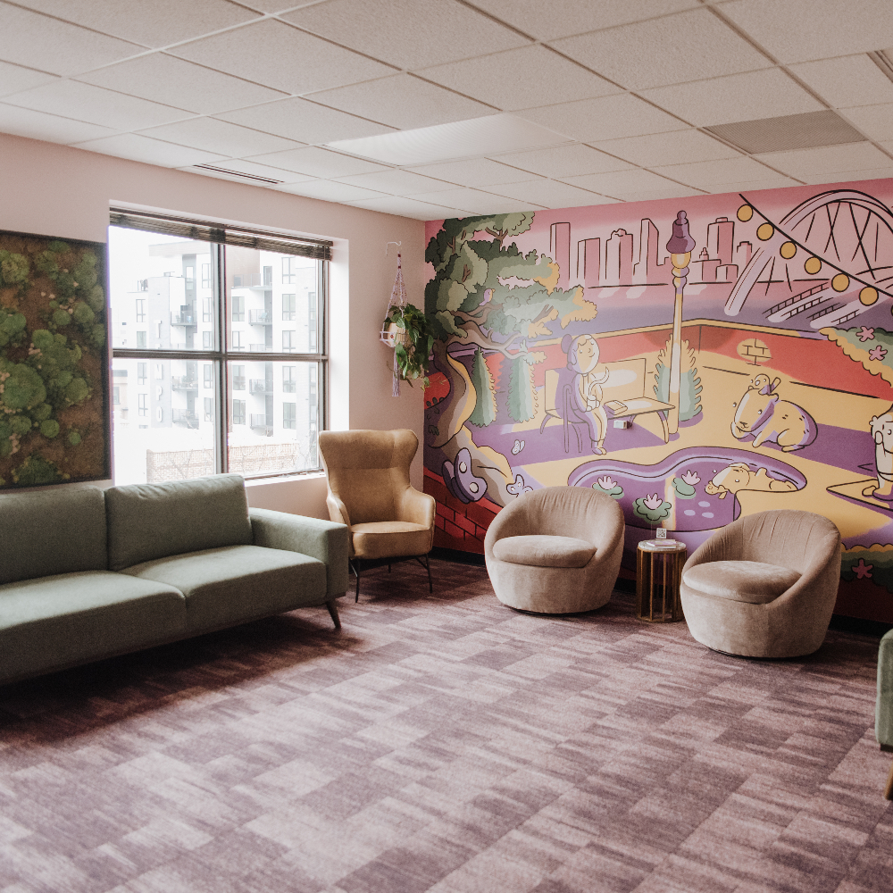 Waiting Room with cozy seating and a colorful mural on the wall.