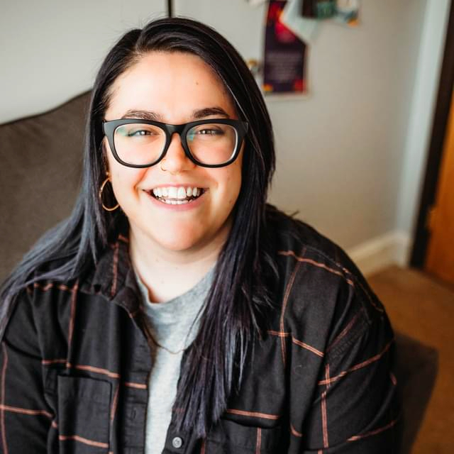 Person wearing glasses smiling at the camera.