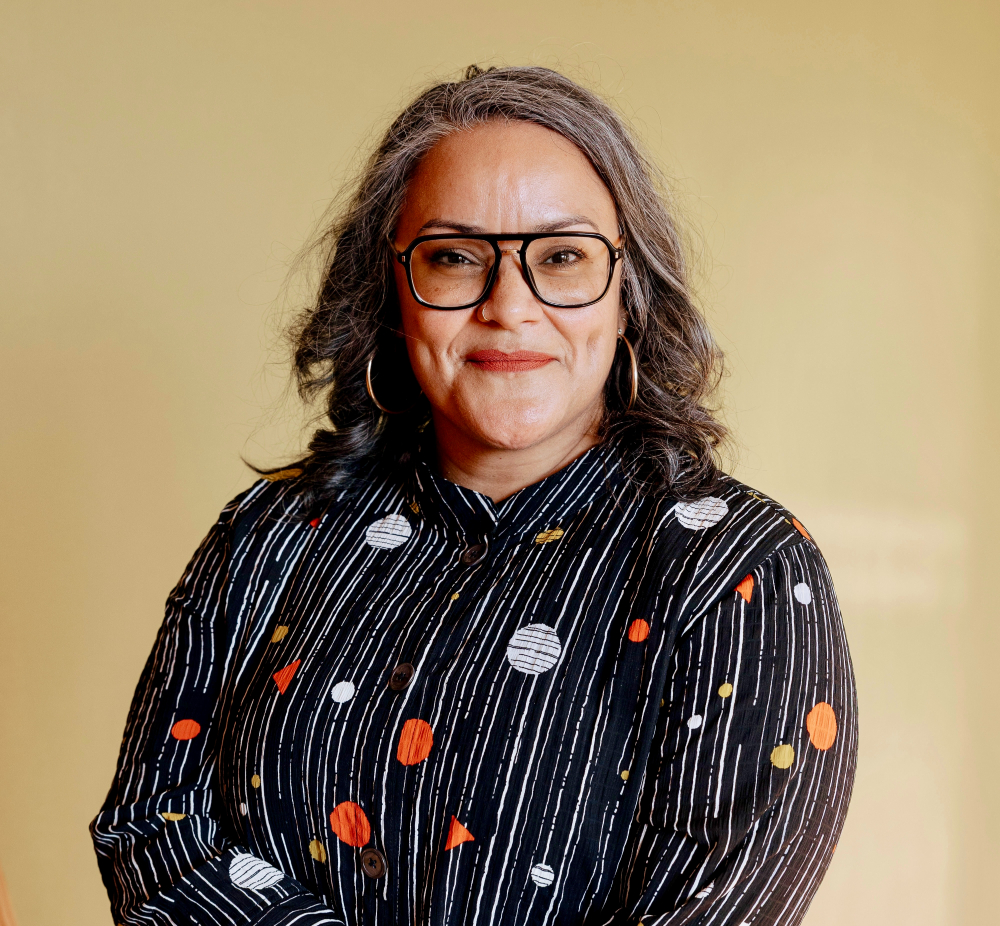 Person wearing blue glasses and a patterned top.