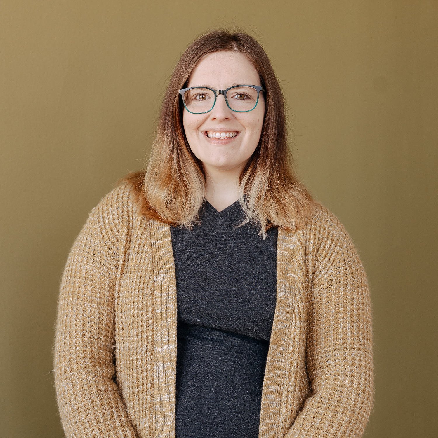 Person in a t-shirt and cardigan smiling at the camera.